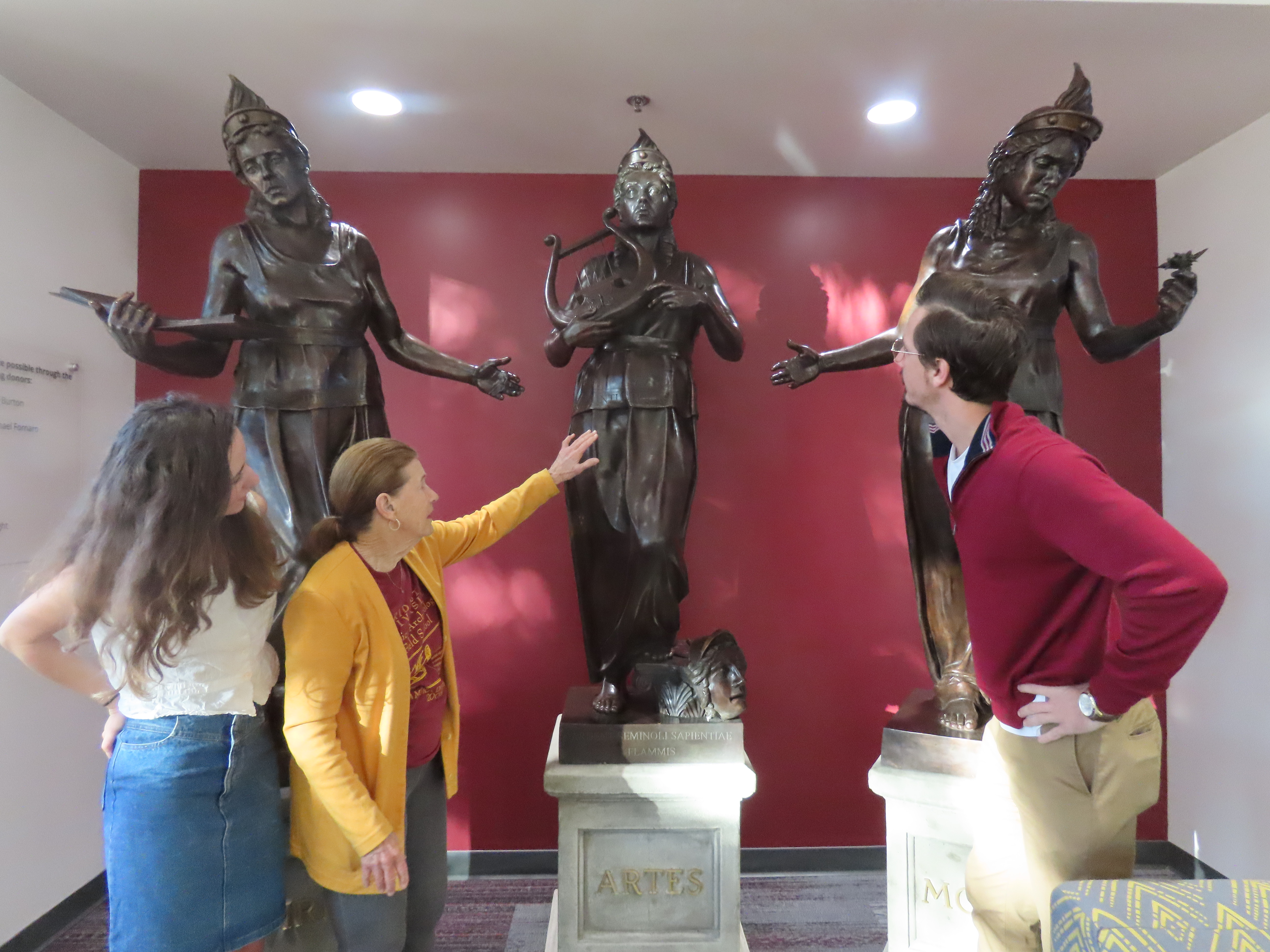 Photo of Dr. Nancy de Grummond and grad students inspecting the three statues: Vires, Artes, and Mores.