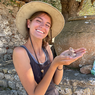 Image of Allisen Hunter holding an artifact at a dig site